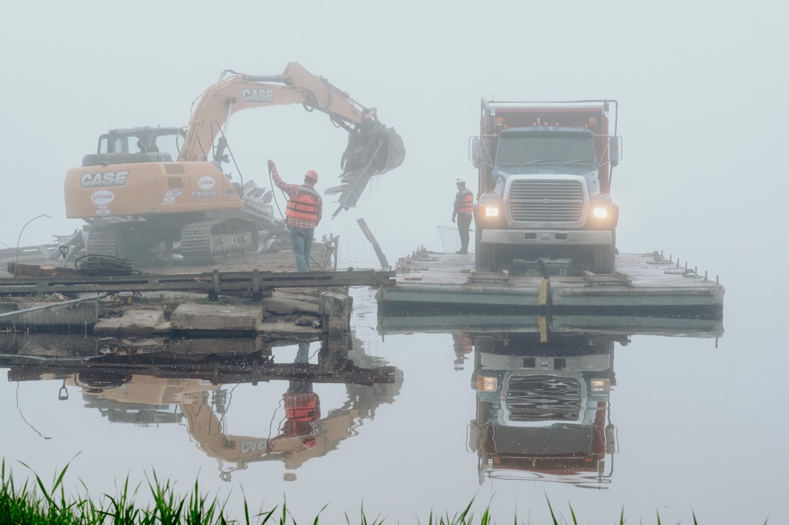 An LJJ excavator and dump truck working from a barge in fog